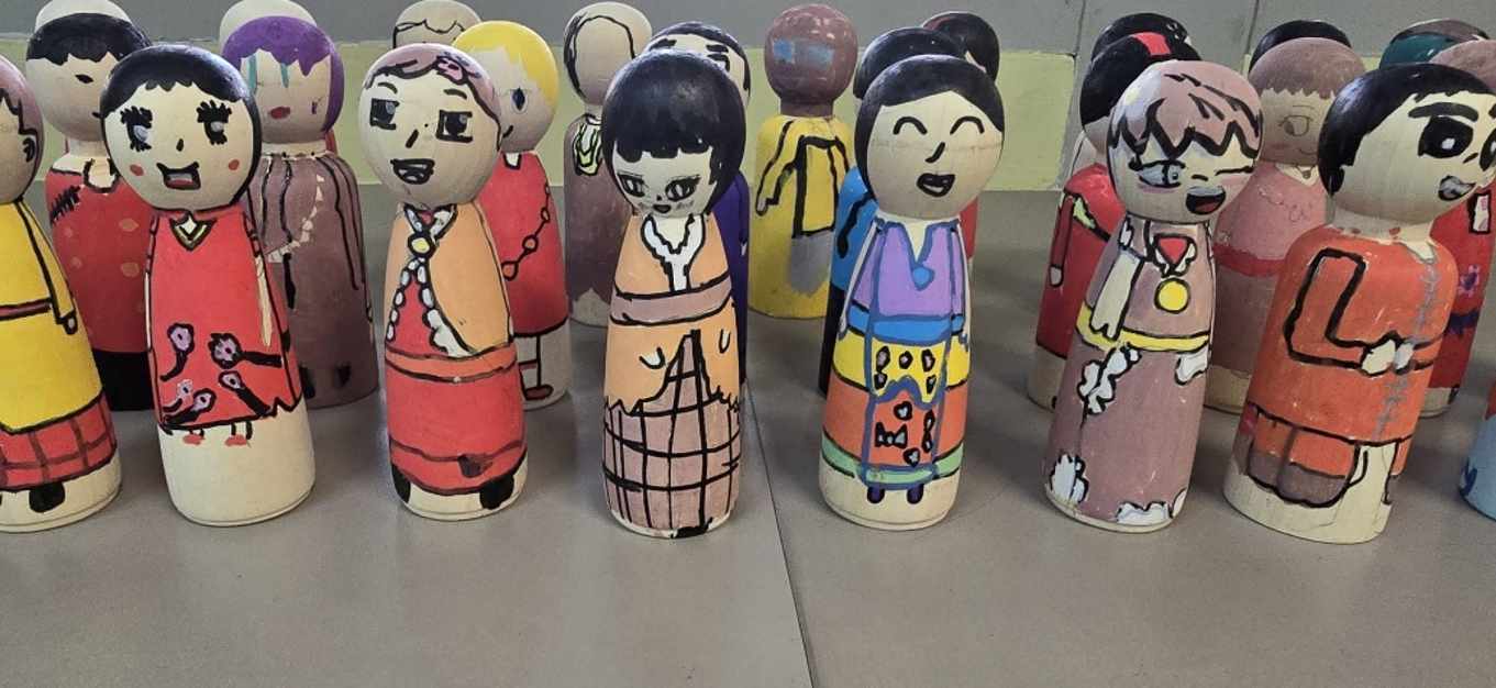 Painted wooden peg dolls created by students for an art project.